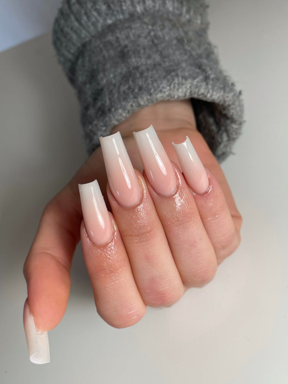 Babyboomer rose et blanc sur ongles longs de forme carrée.