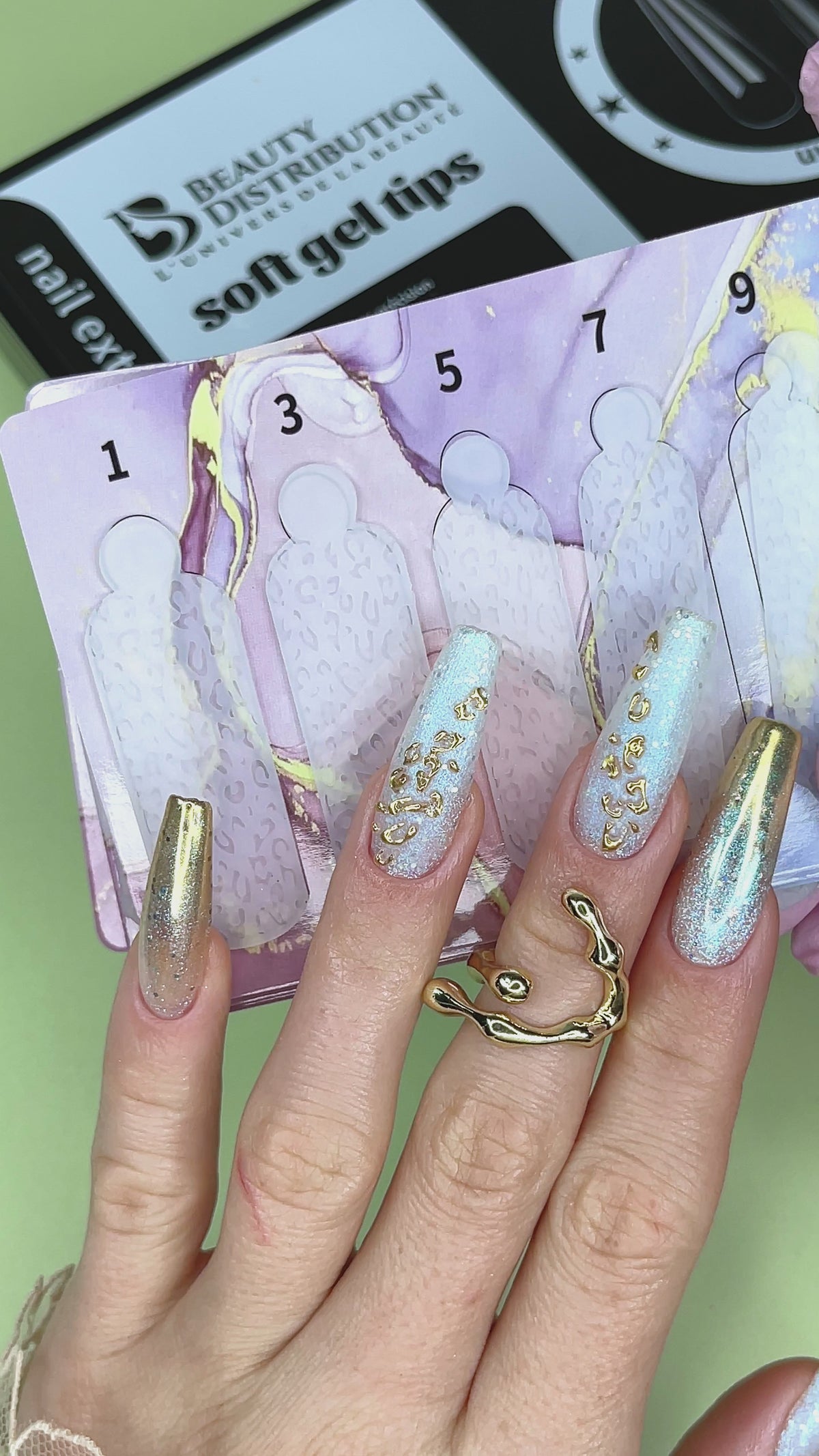 Manucure longue irisée devant un coffret de capsules soft gel