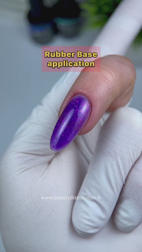 Démonstration complète de la Rubber Base Galactica Beauty Distribution par Nail Champion : flacon, application de la base violette pailletée et résultat. La Rubber Base Clear et la finition sont des produits distincts.
