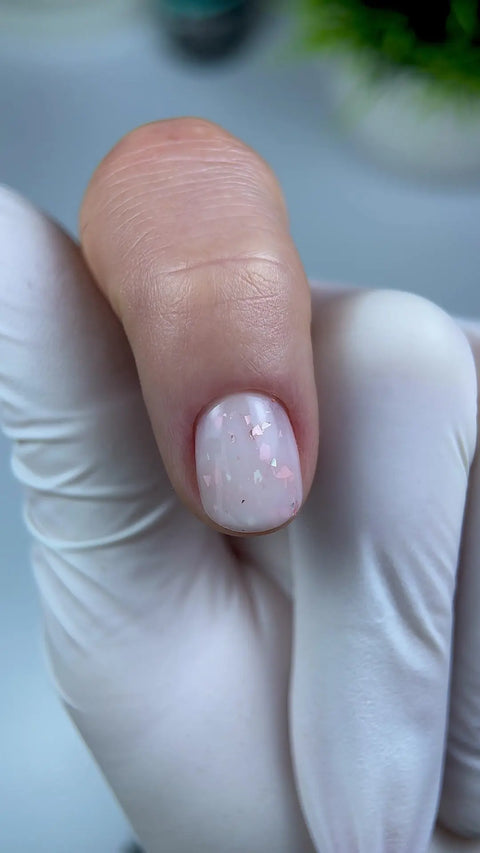 Résultat de la Rubber Base Flakes Beauty Distribution : base laiteuse ornée de flakes roses sur un ongle court, par Nail Champion.